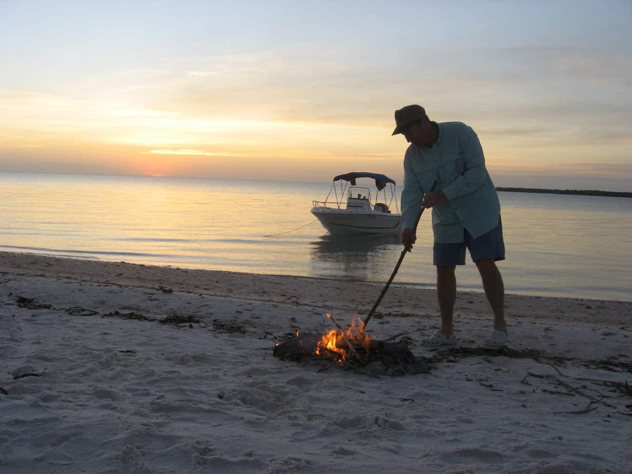 Warren stokes the campfire on the beach at Panther Key.