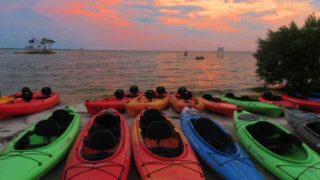 As the sun sets over Merritt Island National Wildlife Refuge, kayaks are lined up ready to launch for a bioluminescent kayak trip. (Photo: Bonnie Gross)