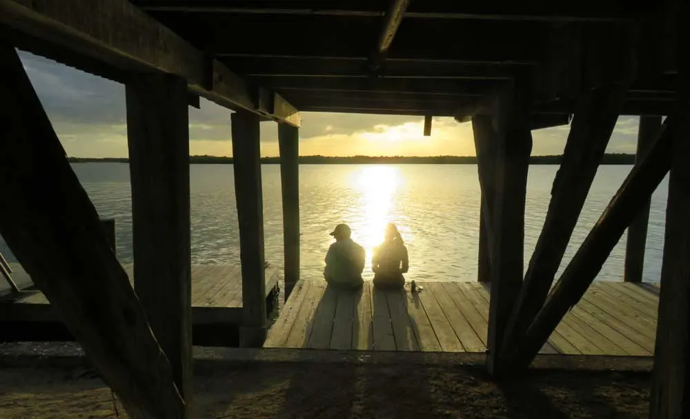 The sun sets over Chokoloskee Bay as two people sit on the dock at Smallwood's Store, a historic site in the little town of Chokoloskee. (Photo: Bonnie Gross)