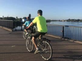 Bicyclists on bridge over water.